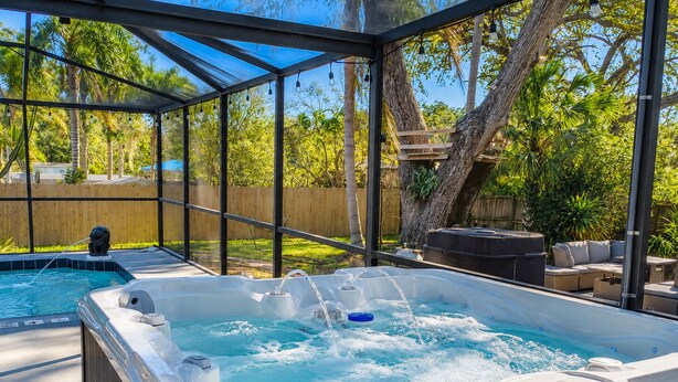 Un bain à remous avec une terrasse en bois, une piscine et du mobilier d’extérieur.