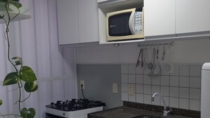 Una cocina moderna con armarios blancos, microondas integrado, estufa a gas y un fregadero.