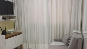 Una sala de estar moderna con un sofá, un reposapiés y un televisor sobre un mueble.