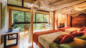 A room with two beds, a table, and a view of the outdoors. - Deluxe Twin Room (Cahuita)