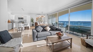 A modern living room with a grey sofa, a coffee table with a bowl, and a view of the ocean through large windows. - Luxury Ocean Front Modern Condo in Rosarito BC (Rosarito)