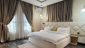 Una habitación de hotel moderna con una cama grande, un cabecero con diseño de diamantes y piso de madera.