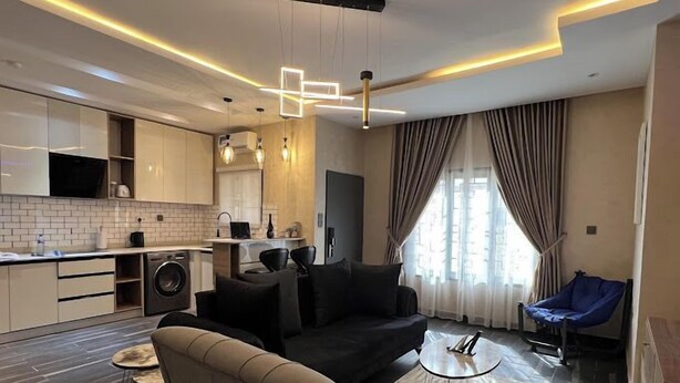 Una sala moderna con un sofá negro, una mesa de centro y una silla azul.