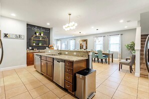 Una cocina moderna con lavavajillas integrado, un letrero que dice 'cafetería' y un comedor con mesa y sillas.