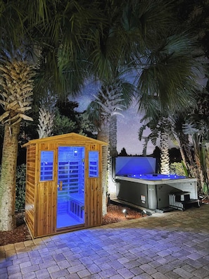 Una estructura de madera con puerta de cristal, un jacuzzi y un cielo estrellado.