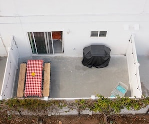 A rooftop patio with a checkered table, a covered seating area, and a small window.