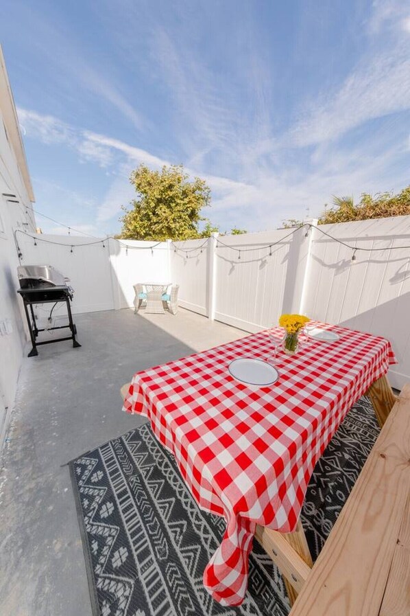 A patio with a checkered table, a small table, and a chair.