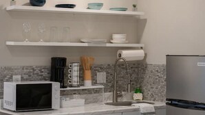Eine moderne Küche mit weißen Schränken, einem Edelstahl-Kühlschrank, einer Mikrowelle und einem Spülbecken.