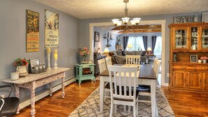 A dining area with a wooden table and chairs, a green sideboard, and a chandelier. - Beautiful Spacious Well-Stocked Home in Downtown Rangeley. Pet & Family Friendly (Rangeley)