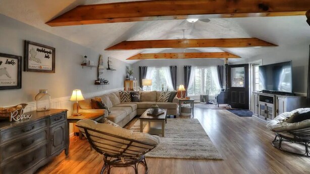 A spacious living room with a wooden ceiling, a sofa set, a coffee table, and a television. - Beautiful Spacious Well-Stocked Home in Downtown Rangeley. Pet & Family Friendly (Rangeley)