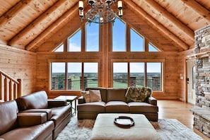 A spacious loft with a high ceiling, large windows, a fireplace, and a cozy seating area.