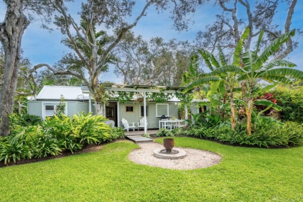 A house with a patio area, surrounded by lush greenery and trees.