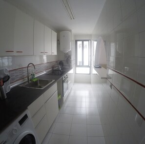 A modern kitchen with white cabinets, a black countertop, and a Bosch washing machine.