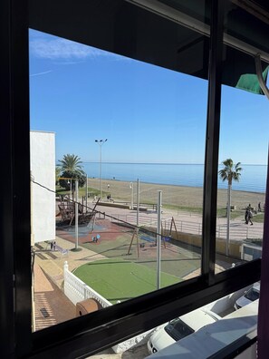 Une vue sur une plage avec une aire de jeux, des palmiers et un ciel bleu dégagé.