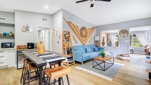 Eine moderne Küche mit Essbereich, einem blauen Sofa und einem Deckenventilator.
