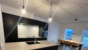 A modern kitchen with a central island, built-in appliances, and a dining area with a long table and chairs.