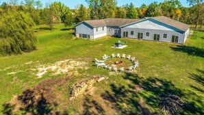 Een twee verdiepingen tellend huis met een ruime achtertuin, een vuurkorf en buitenmeubilair.