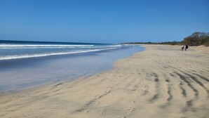 A sandy beach with footprints leading to the water. - One Life Villas (Tamarindo)