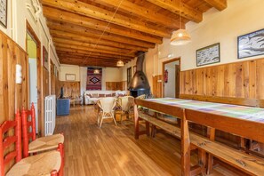 Un interno in legno con un lungo tavolo, sedie in vimini e un camino.