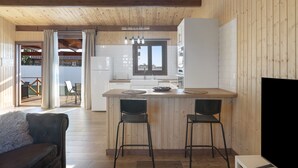 A modern kitchen with wooden beams, a central island with bar stools, and a dining area with a sofa.
