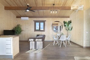 A spacious room with a wooden ceiling, a ceiling fan, a dining area with a table and chairs, a sofa, and a television on a stand. - Villa 'Fatema' with Private Pool, Wi-Fi, and Air Conditioning (Conil de la Frontera)