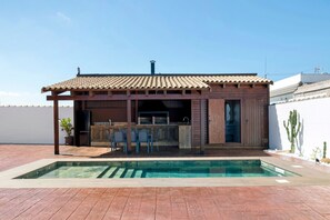 A residential property with a swimming pool, outdoor seating area, and a covered patio.