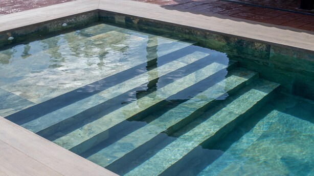 A clear pool with visible steps leading into it.
