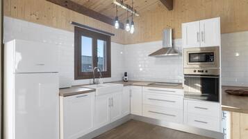 Une cuisine moderne avec des meubles blancs, des appareils en acier inoxydable et un plafond en bois.