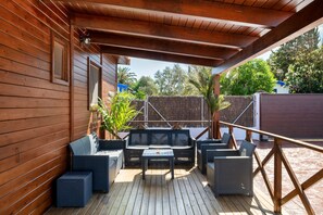 A wooden deck with outdoor furniture, including a table and chairs, and a view of the surrounding area. - Villa 'Fatema' with Private Pool, Wi-Fi, and Air Conditioning (Conil de la Frontera)