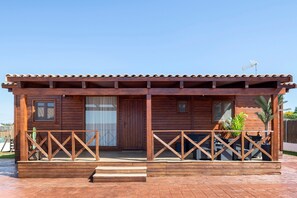 A wooden cabin with a tiled roof, a front door, and a small porch with a railing. - Villa 'Fatema' with Private Pool, Wi-Fi, and Air Conditioning (Conil de la Frontera)