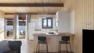 Una cocina moderna con vigas de madera, una isla central con taburetes y vistas a una terraza exterior.
