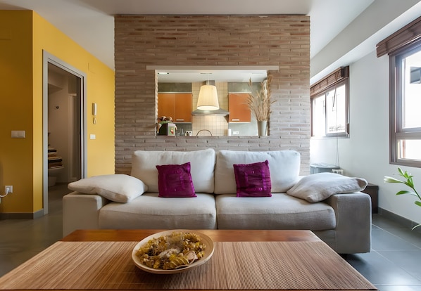 Un salon moderne avec un canapé, une table basse et une cuisine en arrière-plan.
