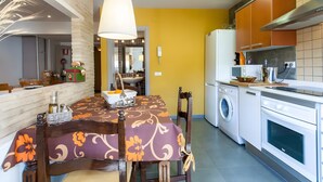 Eine moderne Küche mit Essbereich, darunter ein Tisch mit Blumenmuster, eine Waschmaschine und ein Kühlschrank.