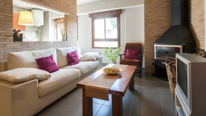 Ein Wohnzimmer mit einer Couch, einem Holztisch, einem Kamin und einem Fernseher.