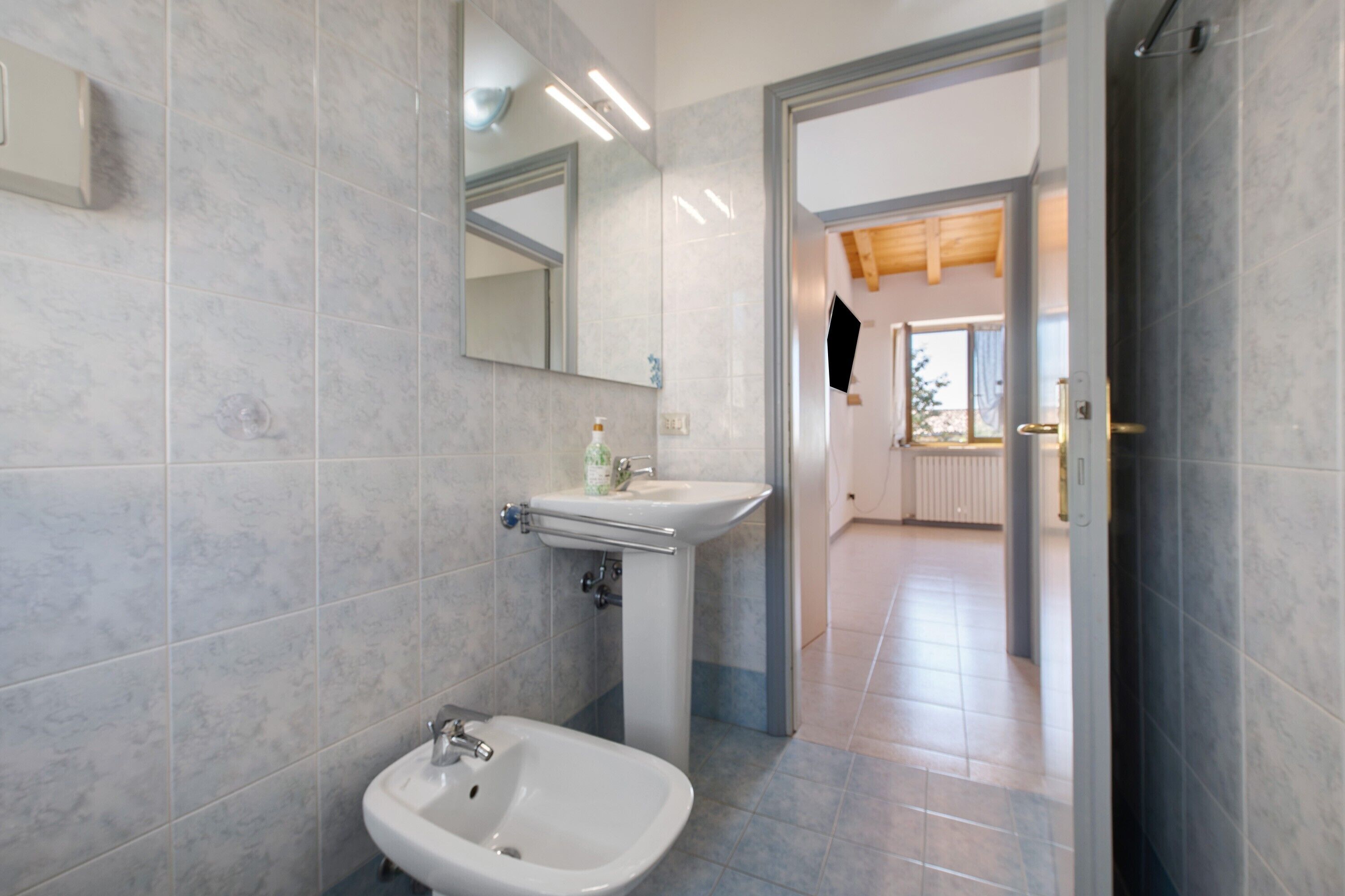 A bathroom with a sink, mirror, and bidet.