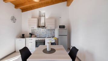 A modern kitchen with white cabinets, a microwave, and a dining table with chairs.