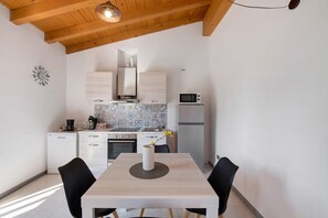 Une cuisine moderne avec des meubles blancs, un four à micro-ondes et une table à manger avec des chaises.
