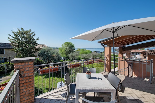 Une terrasse avec une table et des chaises, un pot de fleurs et une vue sur la mer.