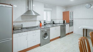 Una cucina con cappa in acciaio inox, lavatrice integrata, forno a microonde e lavello.