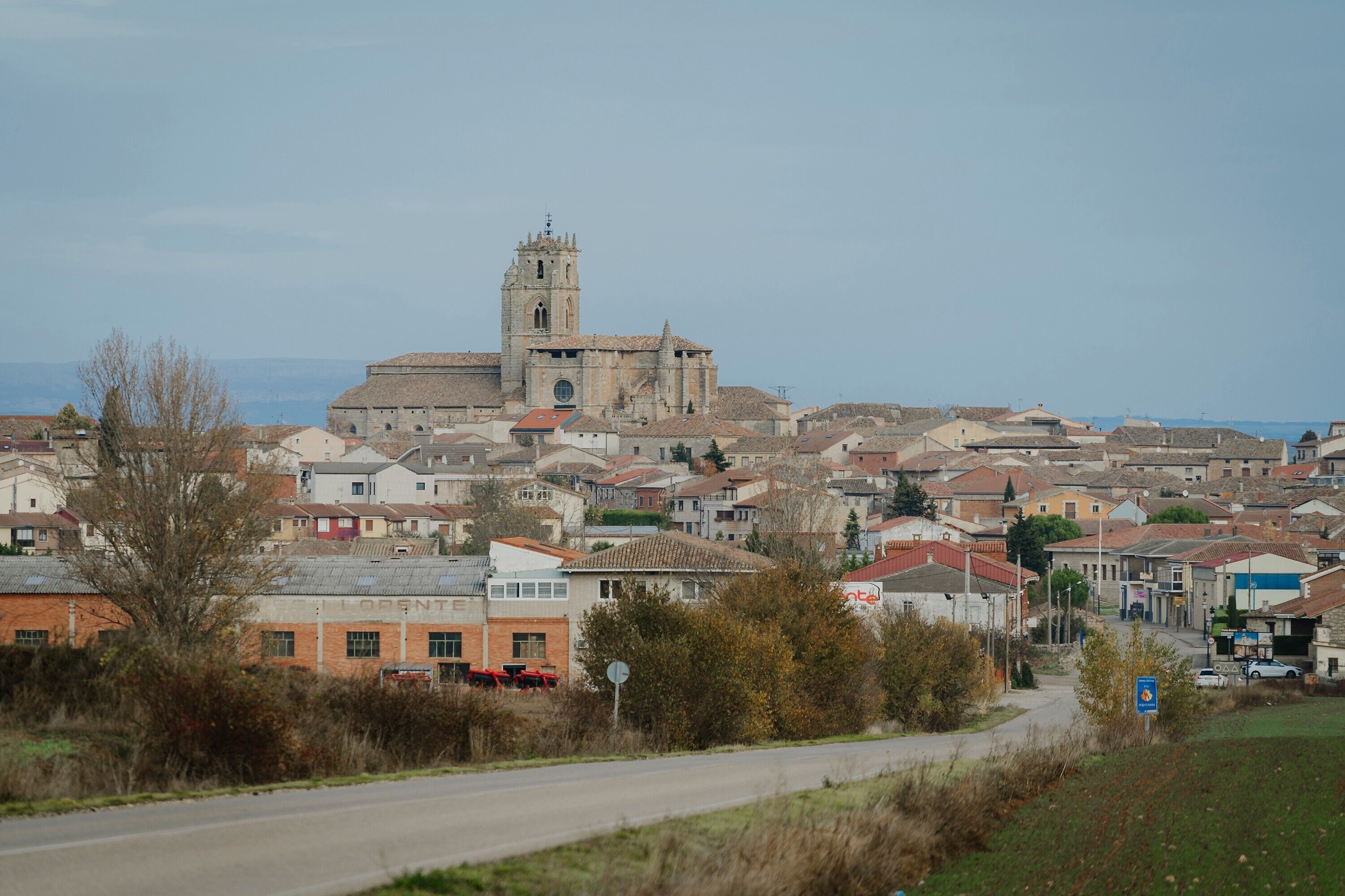 Un pueblo con una iglesia destacada que cuenta con una torre alta, rodeado de edificios residenciales.