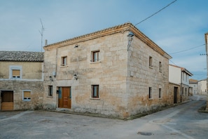 A stone building with a tiled roof, a wooden door, and a small window. - Country House 'El Humilladero' with Private Terrace (Sasamón)