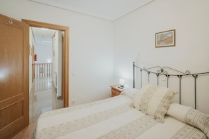 A bedroom with a bed, a nightstand, a wall-mounted lamp, and a door leading to another room. - Country House 'El Humilladero' with Private Terrace (Sasamón)