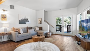 A modern living room with a grey sectional sofa, a round coffee table, and a white furry rug.
