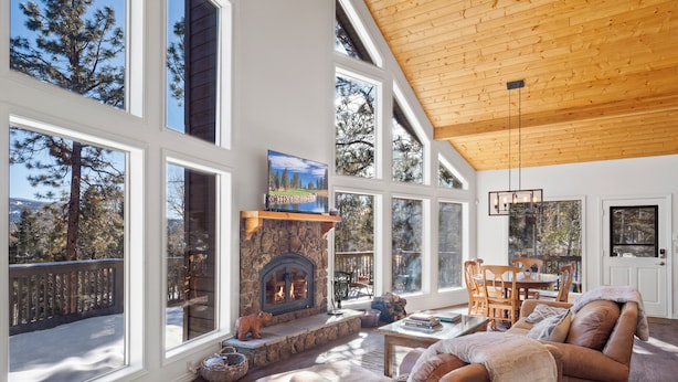 A spacious living room with a stone fireplace, large windows, and a cozy seating area.