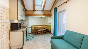 A compact kitchen with a dining area, a built-in microwave, and a small refrigerator. - Apartment 'Appartamento Condominio Genziana' with Mountain View, Balcony and Wi-Fi (Dimaro Folgarida)