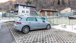 A car parked in a paved area with a mountainous backdrop. - Apartment 'Appartamento Condominio Genziana' with Mountain View, Balcony and Wi-Fi (Dimaro Folgarida)