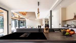 Una cocina moderna con un fogón de inducción negro, un frutero y una lámpara colgante.