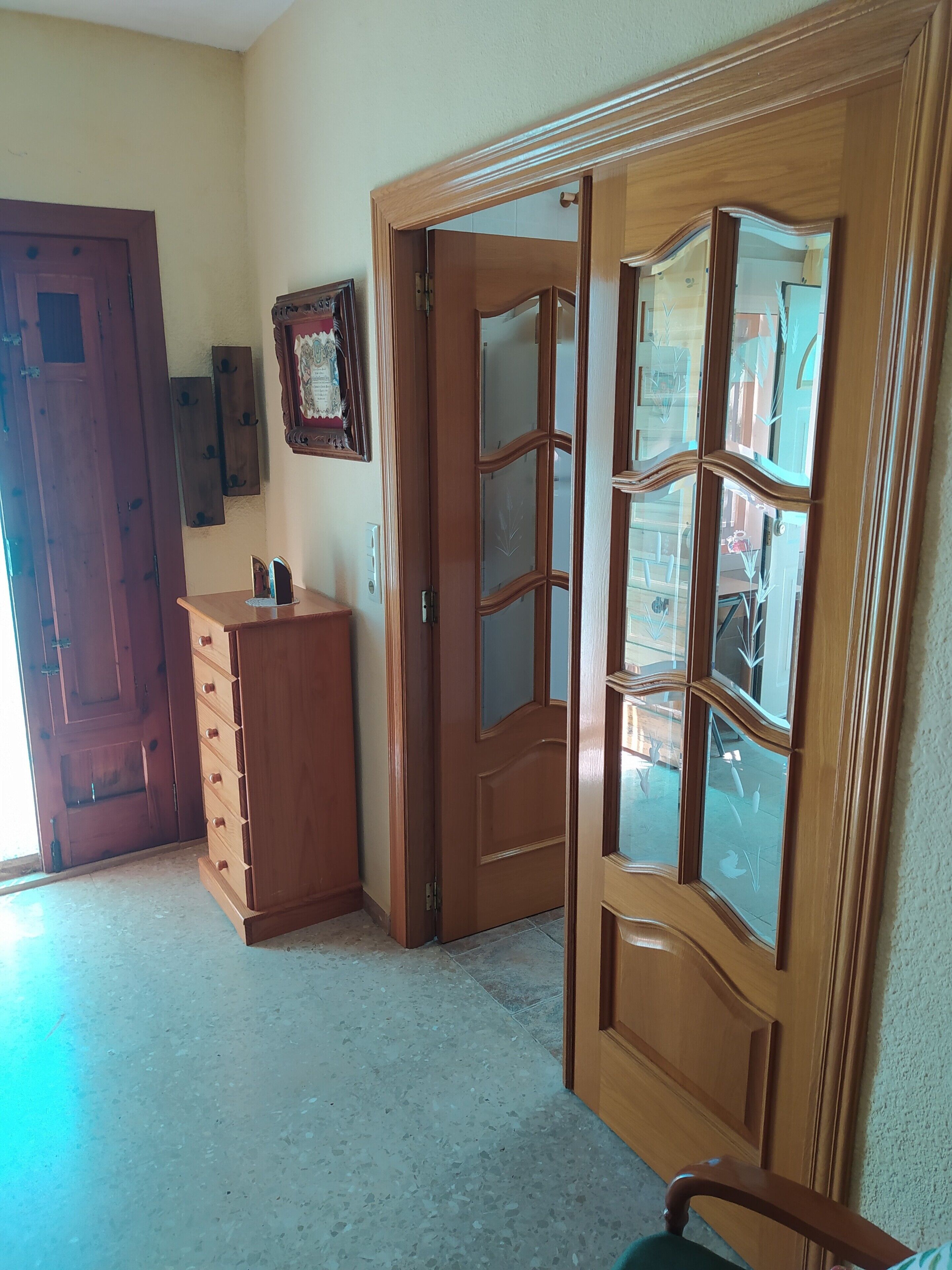 A hallway with a wooden door, a wooden cabinet, and a mirror.
