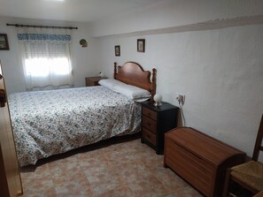 Un dormitorio con cama, mesita de noche, cómoda y lámpara.