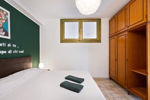A bedroom with a bed, a wardrobe, a window, and a wall with a painting.